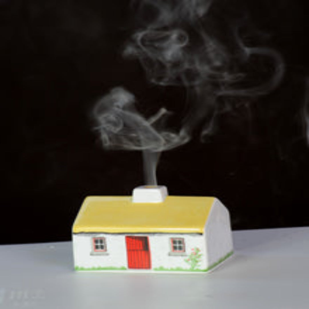 Model house with smoke coming out of a chimney against a dark background