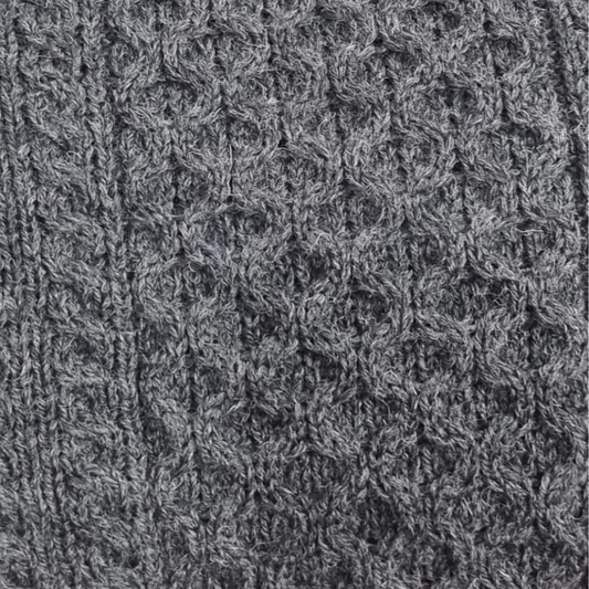 Close-up of charcoal grey Aran sweater showing honeycomb stitch and cable knit detail