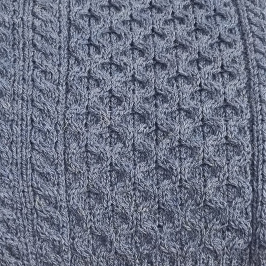 Close-up of denim blue Aran sweater showing honeycomb stitch and cable knit detail