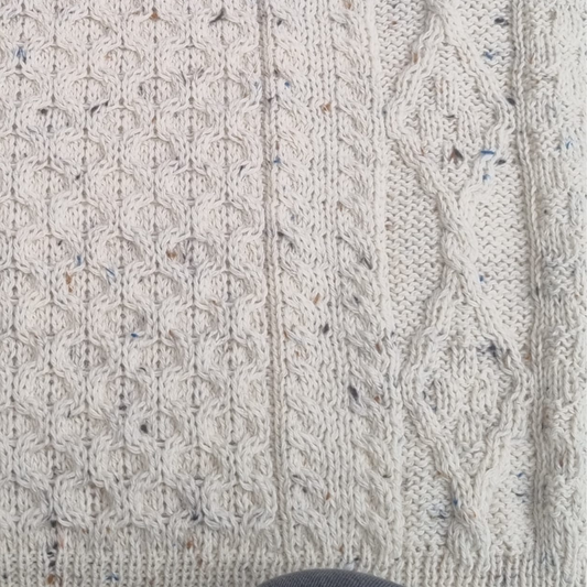 Close-up of flecked wool Aran sweater showing honeycomb stitch and cable knit detail