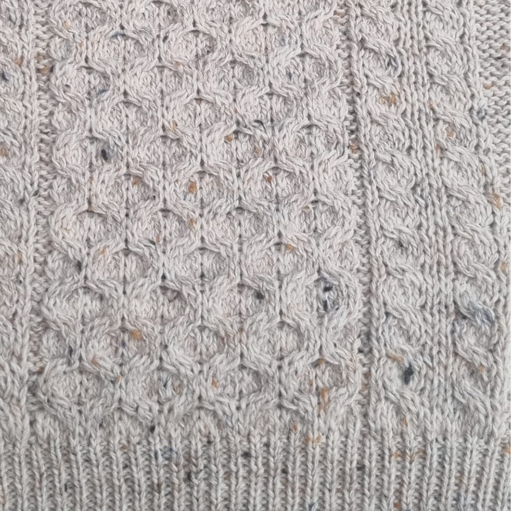 Close-up of oatmeal Aran sweater showing honeycomb stitch and cable knit detail