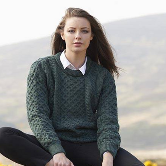 Woman in green Aran crew neck sweater, showcasing authentic Irish knitwear in soft merino wool.