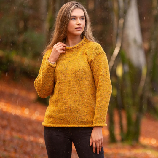 Woman wearing mustard roll neck tunic, hand loomed in Donegal from 100% wool, standing in autumn woodland