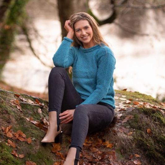 Woman sitting outdoors wearing turquoise roll neck tunic, hand loomed in Donegal from 100% wool