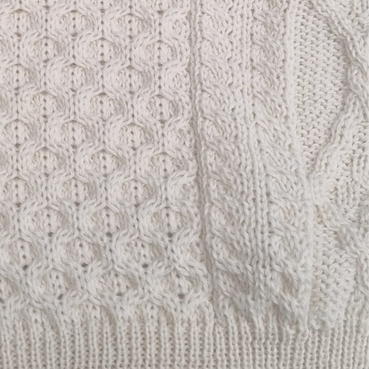 Close-up of natural cream Aran sweater showing honeycomb stitch and cable knit detail

