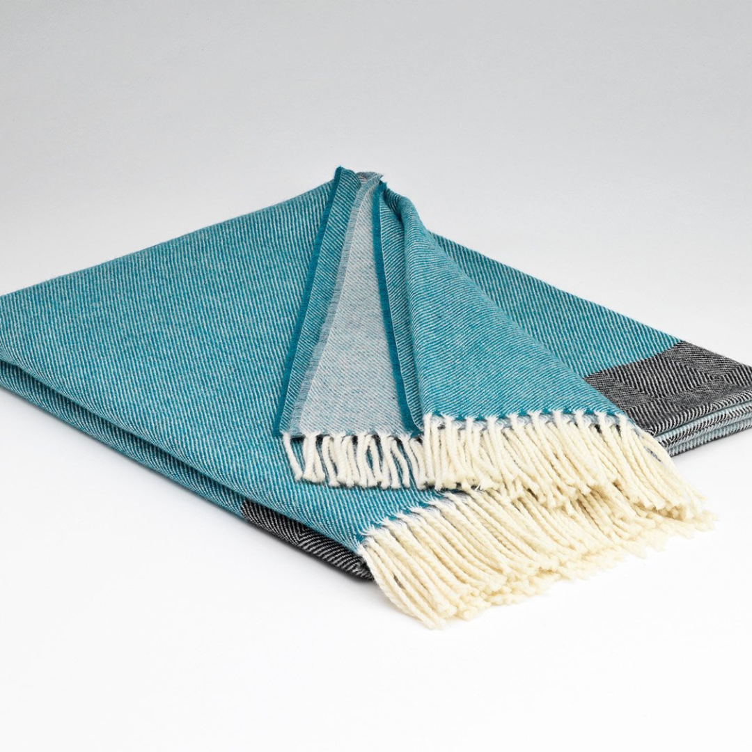 Folded Vienna merino lambswool throw showing blue and charcoal design with fringe