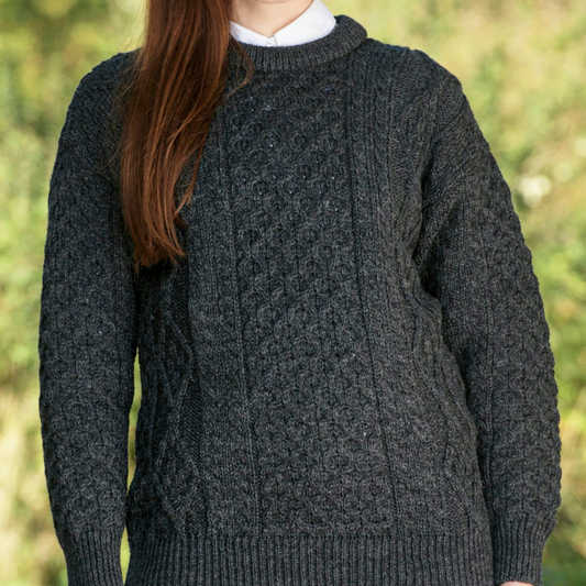 Woman wearing charcoal grey crew neck Aran sweater with traditional Irish stitches, made from 100% merino wool