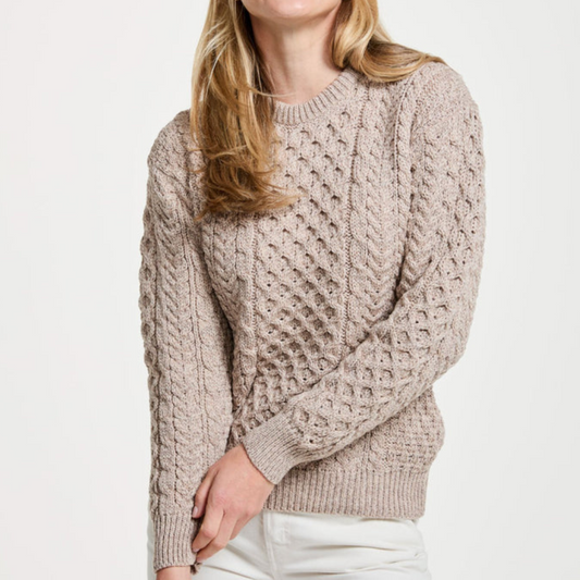 Woman wearing oatmeal crew neck Aran sweater with traditional Irish stitches, made from 100% merino wool